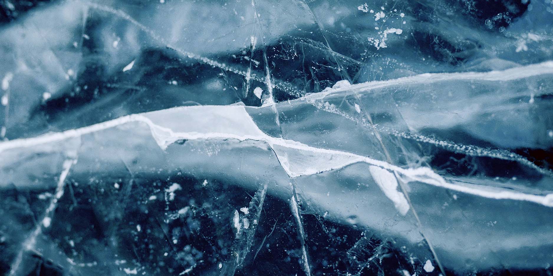 Zoomed in photo of white cracks against dark blue ice