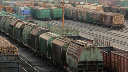 Train cars at a railyard stacked high with logs