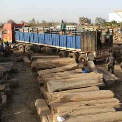 Photo of a blue supply truck in Mali surrounded by workers and logs from all sides