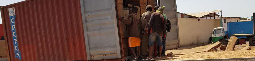 A group of workers crowd around a container stacked with logs