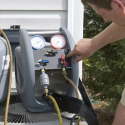 A person holding a phone monitors a series of wire connecting a machine, a gas container, and an air conditioner unit