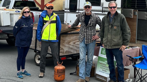 A group of volunteers in a recycling drive pose next to their equiptment