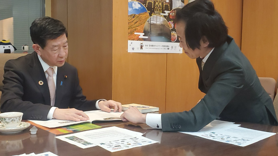 Two men examine an array of documents on a table