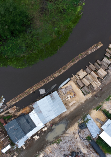 An aerial view of a river shoreline covered in piles of wooden planks