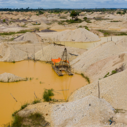 An abandoned boat floats on a polluted yellow pool, surrounded by piles of rubble
