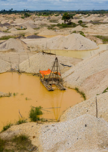 An abandoned boat floats on a polluted yellow pool, surrounded by piles of rubble