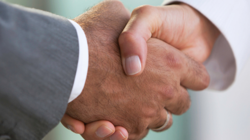Two people in suits shake hands