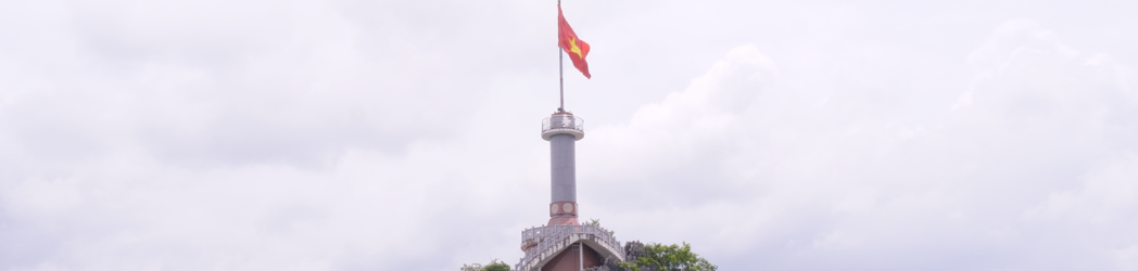 The Vietnamese flag waves over a tower on top of a hill