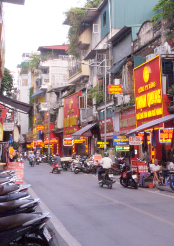 Motorbikes travel down a narrow lane lined with shops