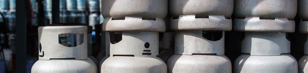 Unlabeled gas canisters stacked with more visible in the distance