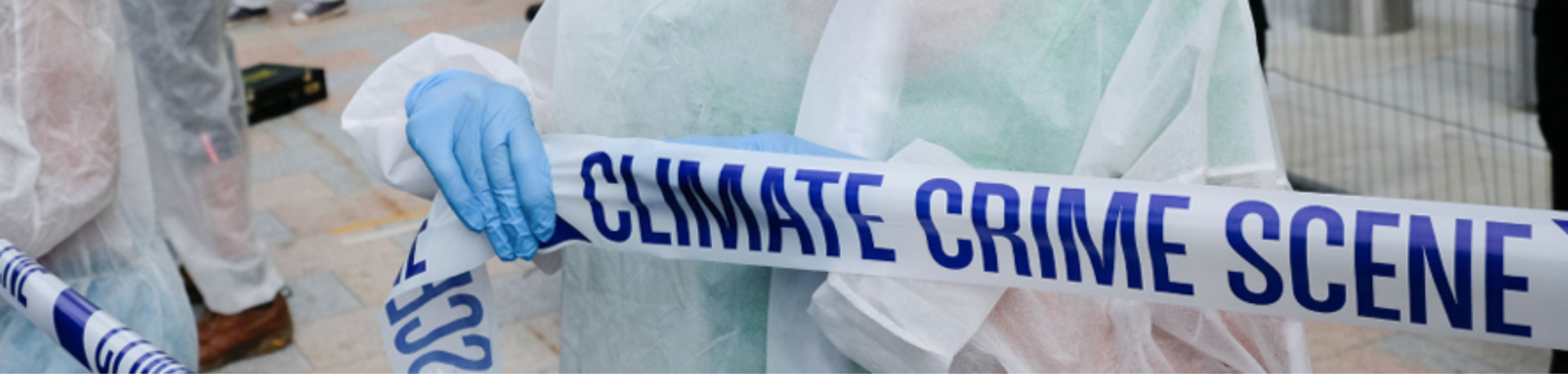 Activist in medical garb holds up police-style tape reading Climate Crime Scene