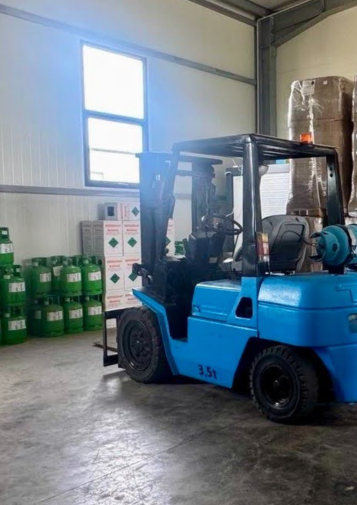 Forklift surrounded by boxes and containers of refrigerant in a warehouse