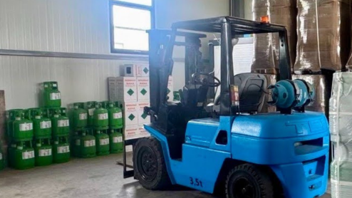 Forklift surrounded by boxes and containers of refrigerant in a warehouse